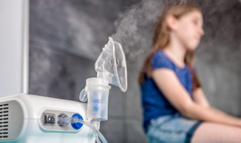 Little girl waiting for medical inhalation treatment with a nebulizer