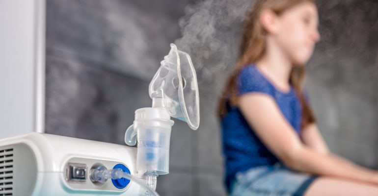 Little girl waiting for medical inhalation treatment with a nebulizer